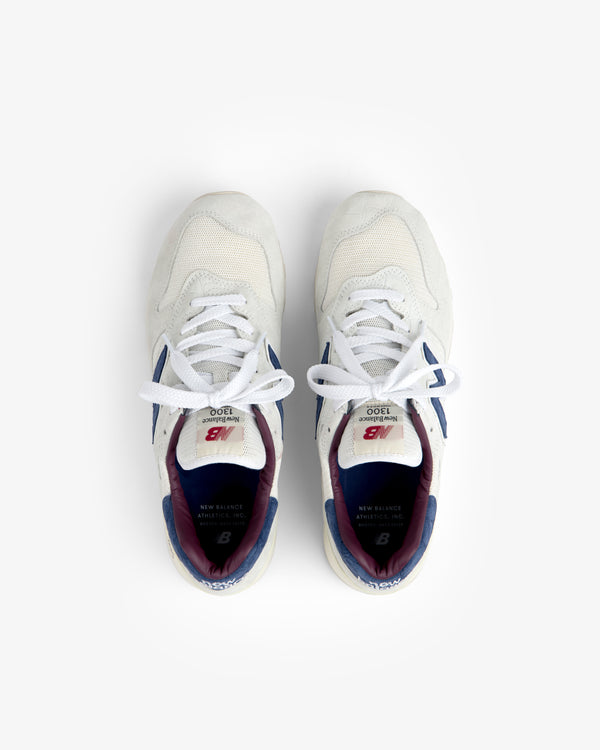 New Balance Made in USA 1300 sneakers in white with blue and maroon accents, shown from above on a white background.