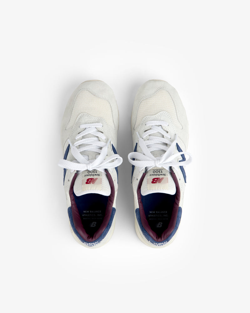 New Balance Made in USA 1300 sneakers in white with blue and maroon accents, shown from above on a white background.