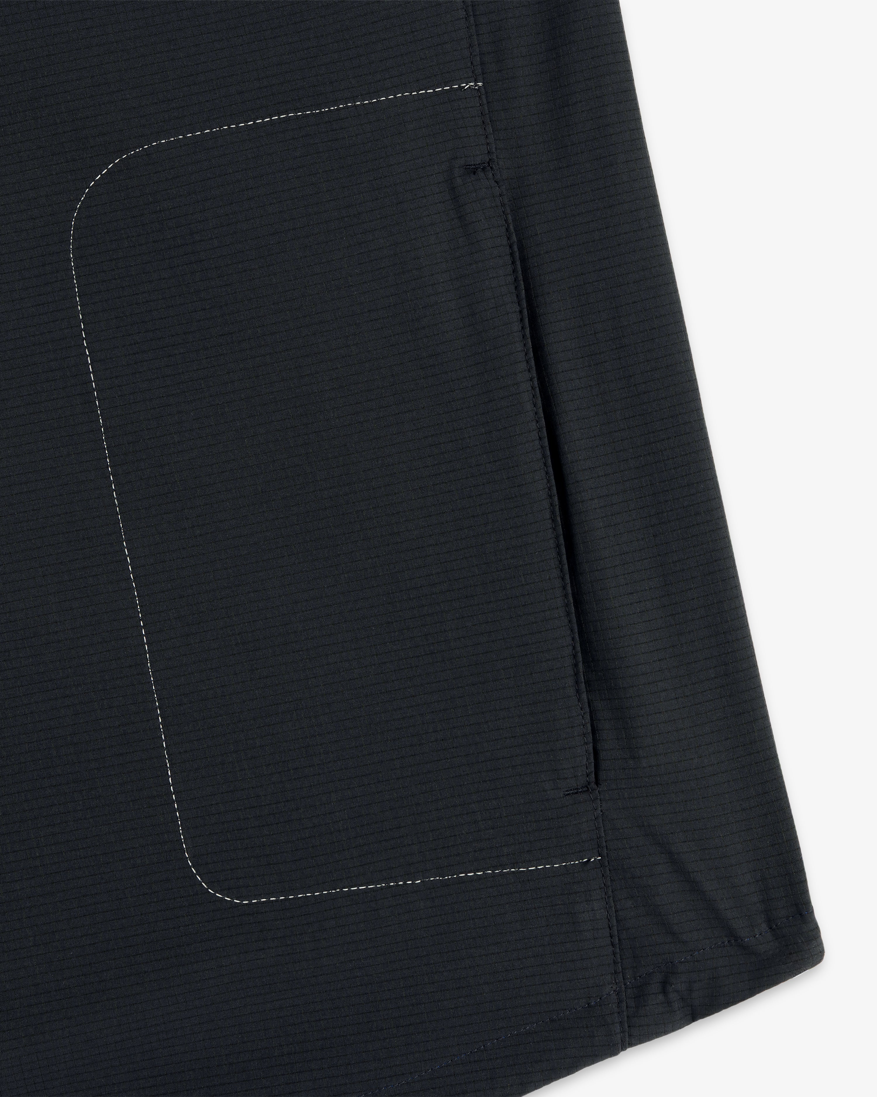 Close-up of the ALD / New Balance Performance Nylon Jacket’s dark fabric pocket with white side stitching.