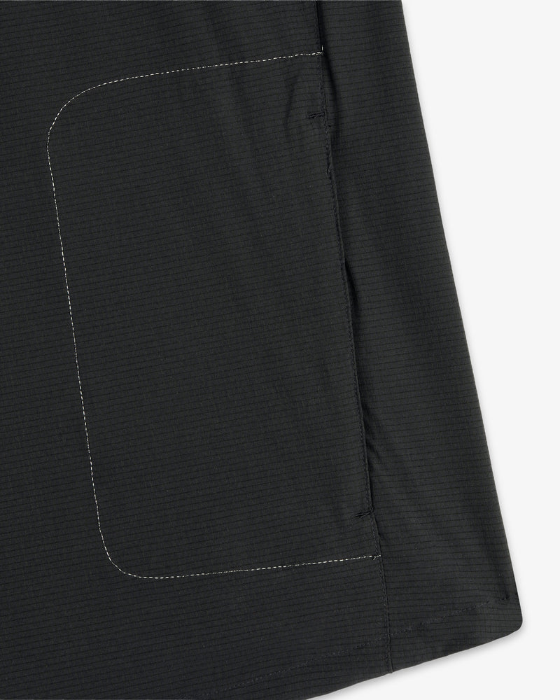 Close-up of a black pocket with white stitching on the ALD / New Balance Performance Nylon Jacket, against white.