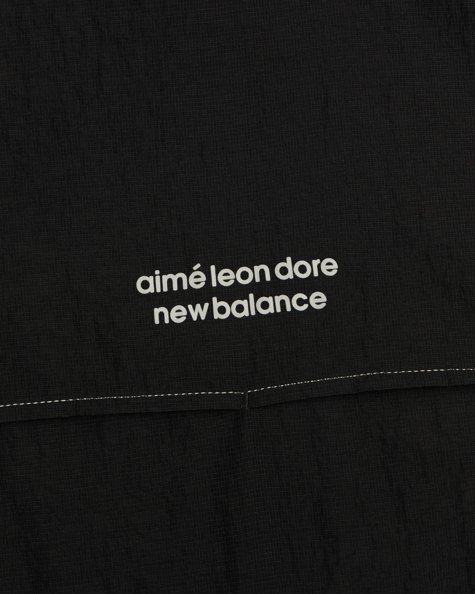 Close-up of black ALD / New Balance Breathable Half-Zip Pullover with white logo above a stitched seam.