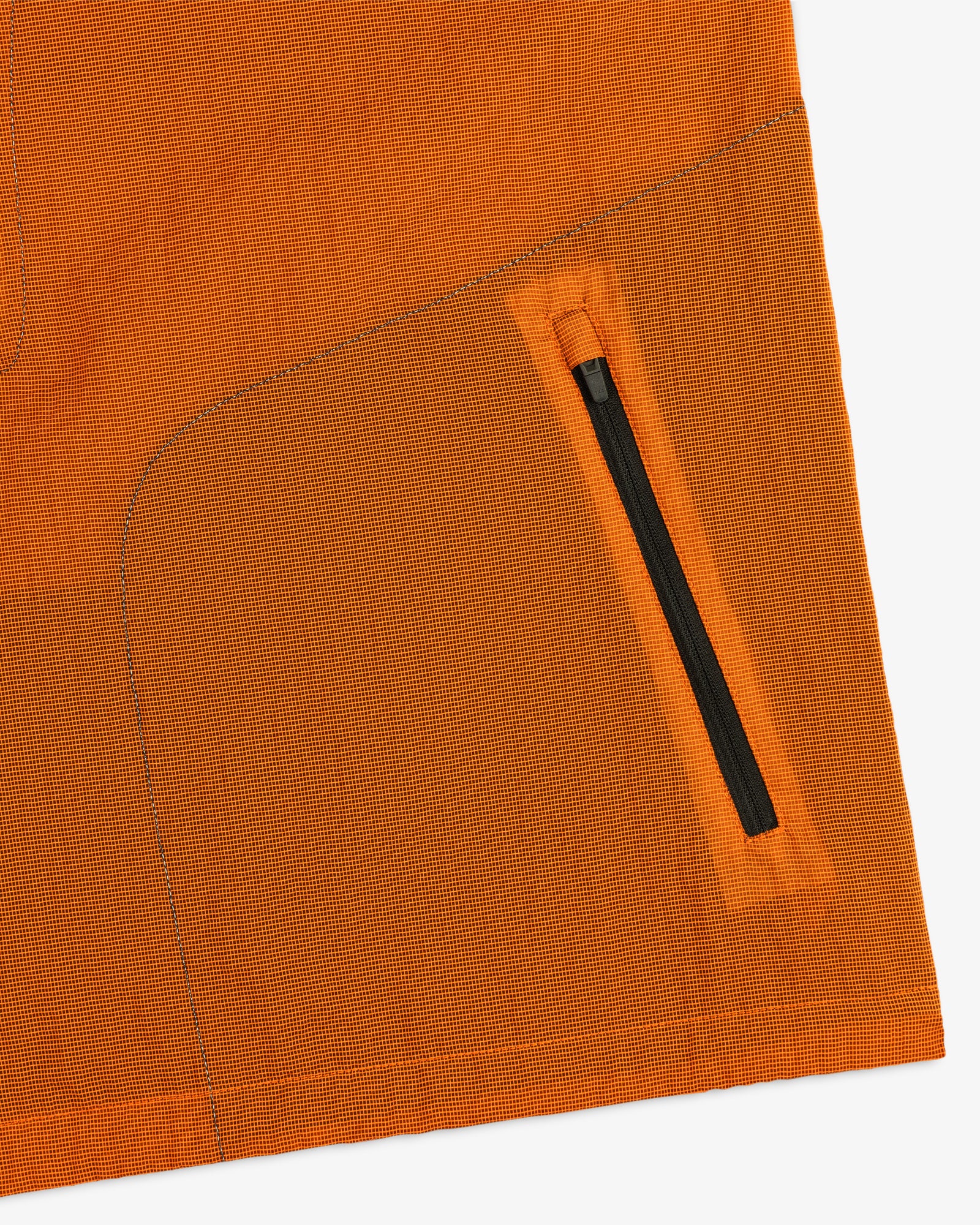 Close-up of the ALD / New Balance Breathable Half-Zip Pullover’s orange fabric, black zipper pocket, and detailed stitching.
