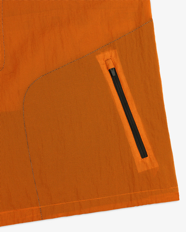 Close-up of the ALD / New Balance Breathable Half-Zip Pullover’s orange fabric, black zipper pocket, and detailed stitching.
