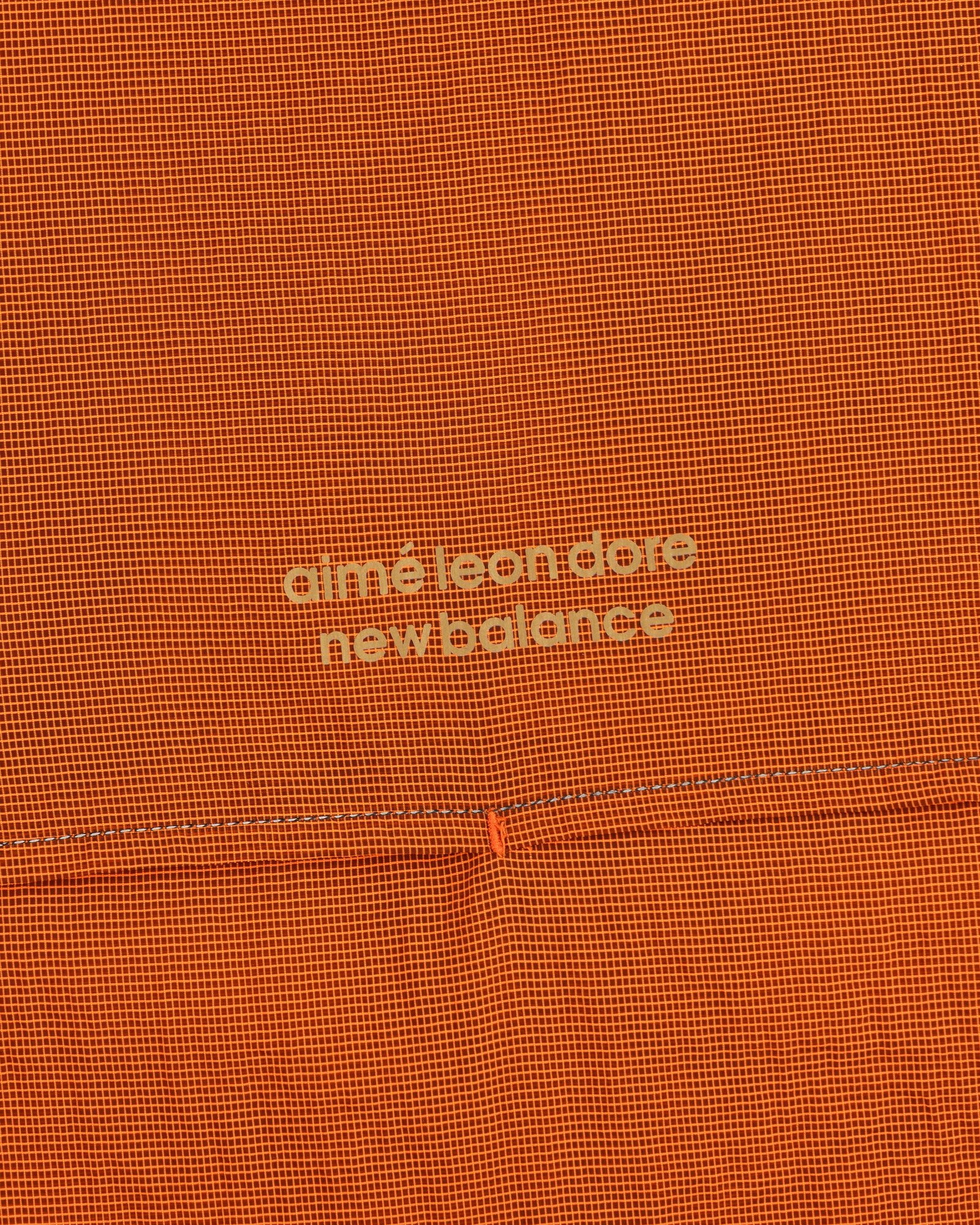 Orange grid-patterned ALD / New Balance Half-Zip Pullover with light yellow text at the center.