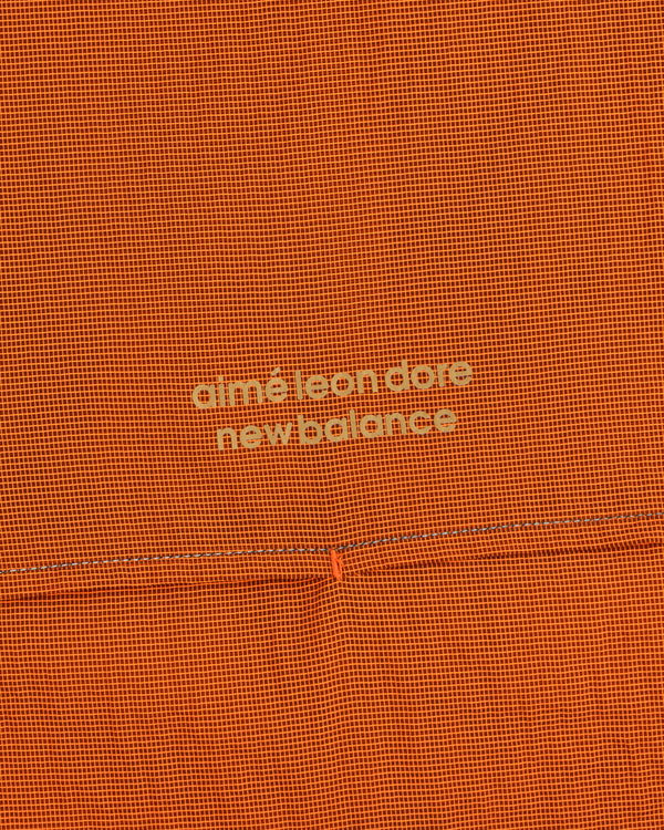Orange grid-patterned ALD / New Balance Half-Zip Pullover with light yellow text at the center.