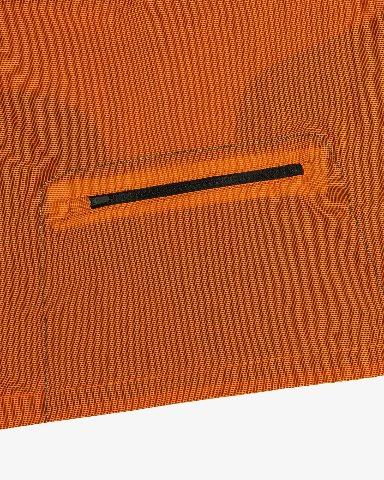 Close-up of the ALD / New Balance Breathable Half-Zip Pullover’s orange fabric with a small black zipper pocket.