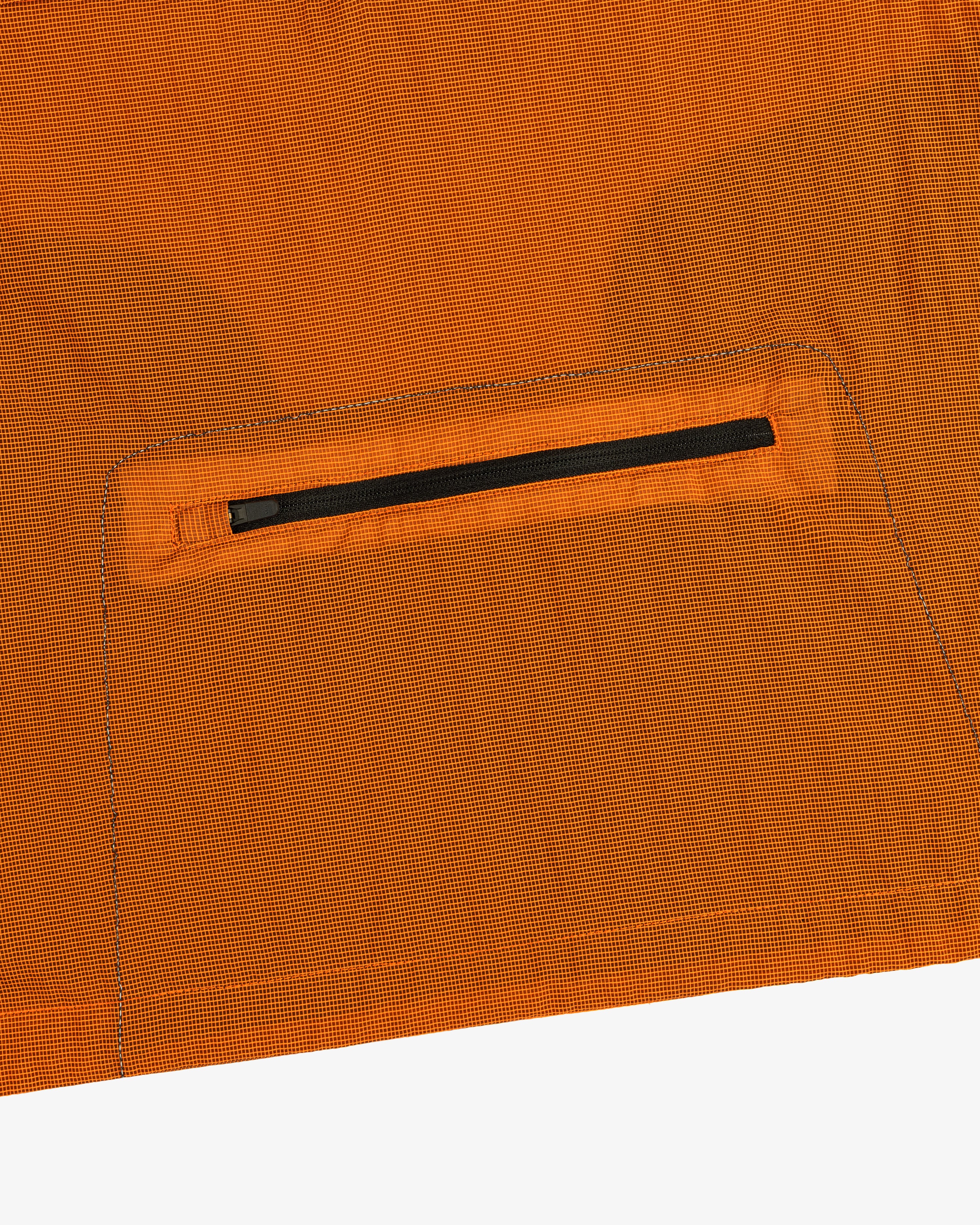 Close-up of the ALD / New Balance Breathable Half-Zip Pullover’s orange fabric with a small black zipper pocket.