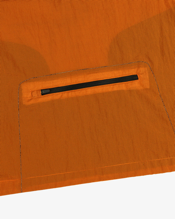 Close-up of the ALD / New Balance Breathable Half-Zip Pullover’s orange fabric with a small black zipper pocket.