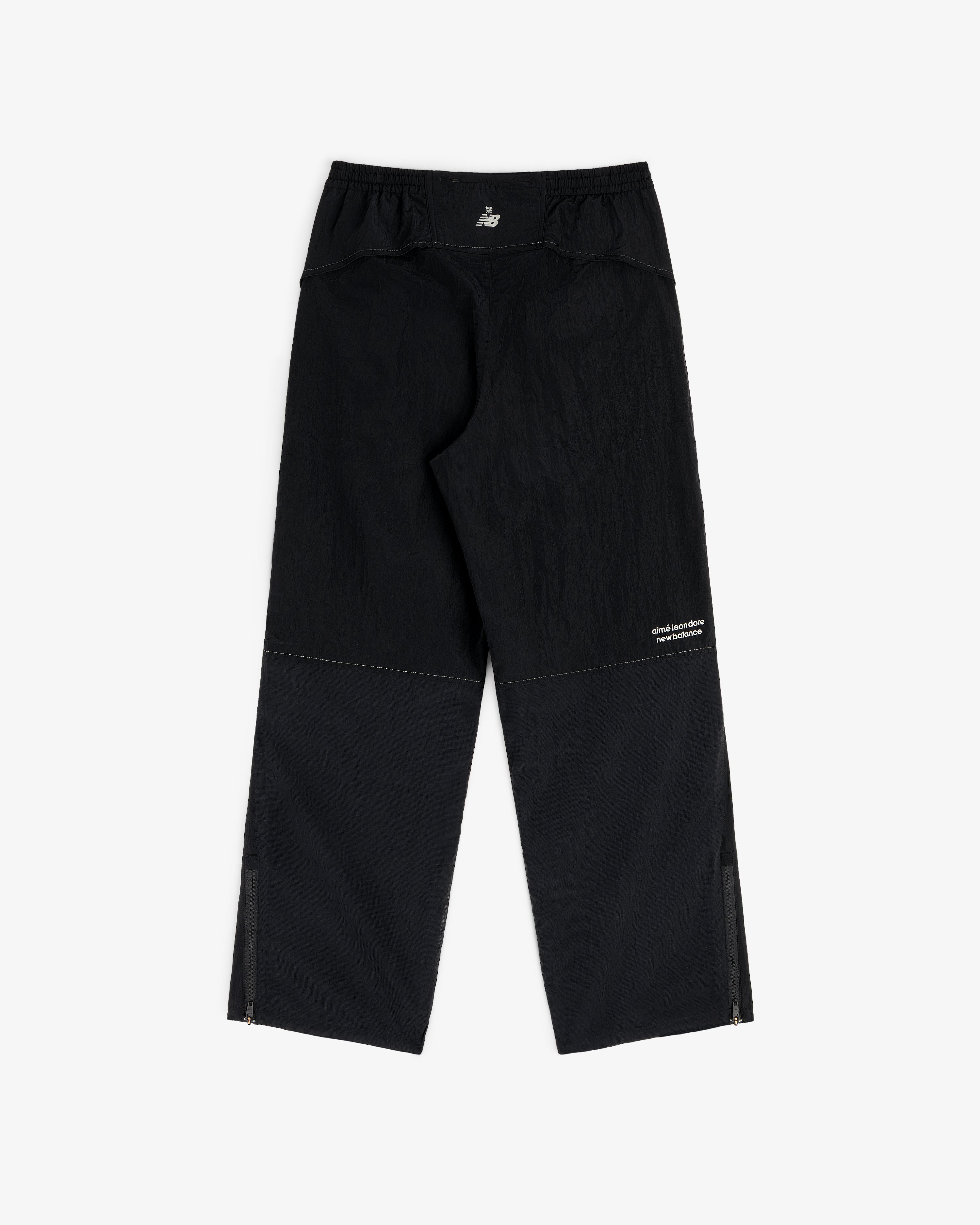 ALD / New Balance Lightweight Nylon Warmup Pant, black with ankle zippers and small white logo, displayed flat.