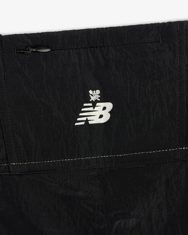 Close-up of the ALD / New Balance Lightweight Nylon Warmup Pant featuring a white logo and snowflake on black fabric.