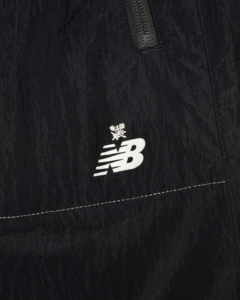 Close-up of black ALD / New Balance Lightweight Nylon Warmup Pant with white logo and small snowflake above it.