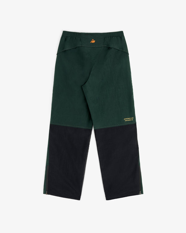 ALD/New Balance warmup pants in dark green/black with yellow logo on waistband and leg, loose fit, lightweight nylon.
