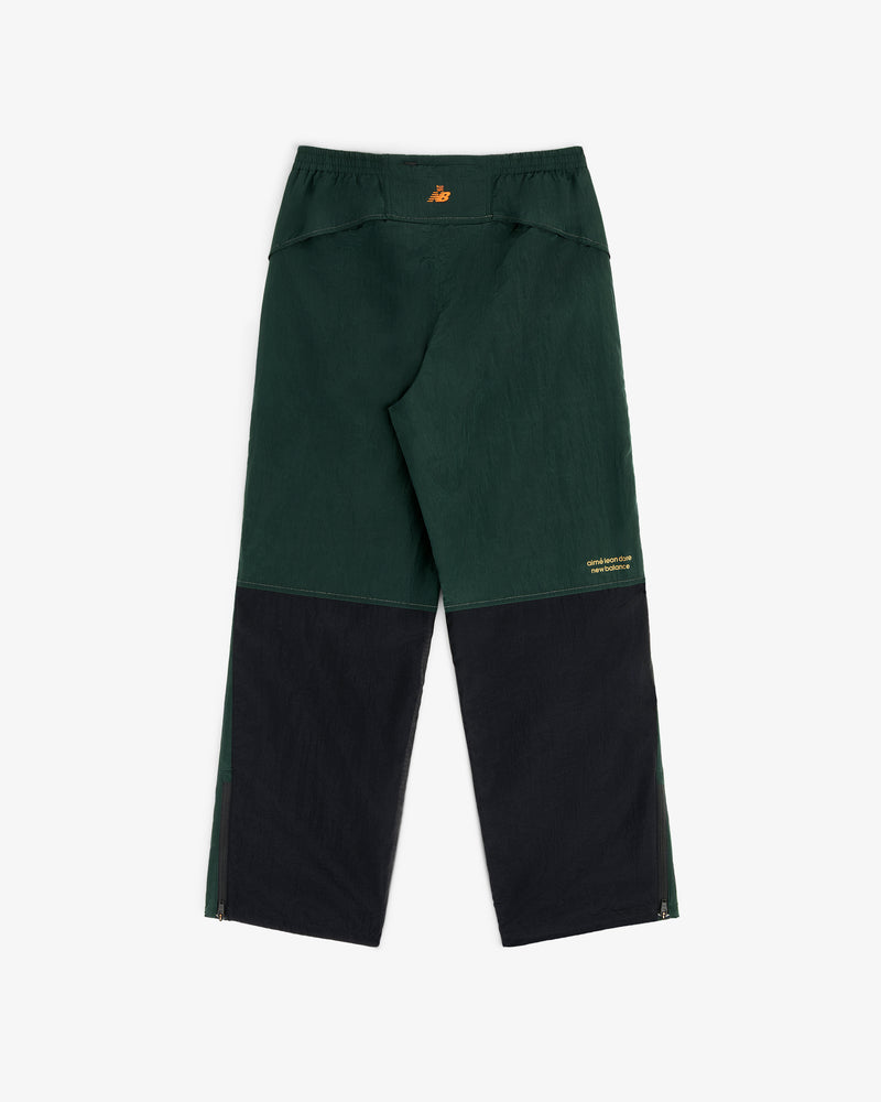 ALD/New Balance warmup pants in dark green/black with yellow logo on waistband and leg, loose fit, lightweight nylon.