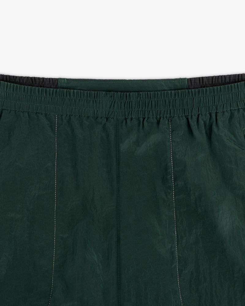 Close-up of the waistband and upper section of the ALD / New Balance Lightweight Nylon Warmup Pant in dark green.