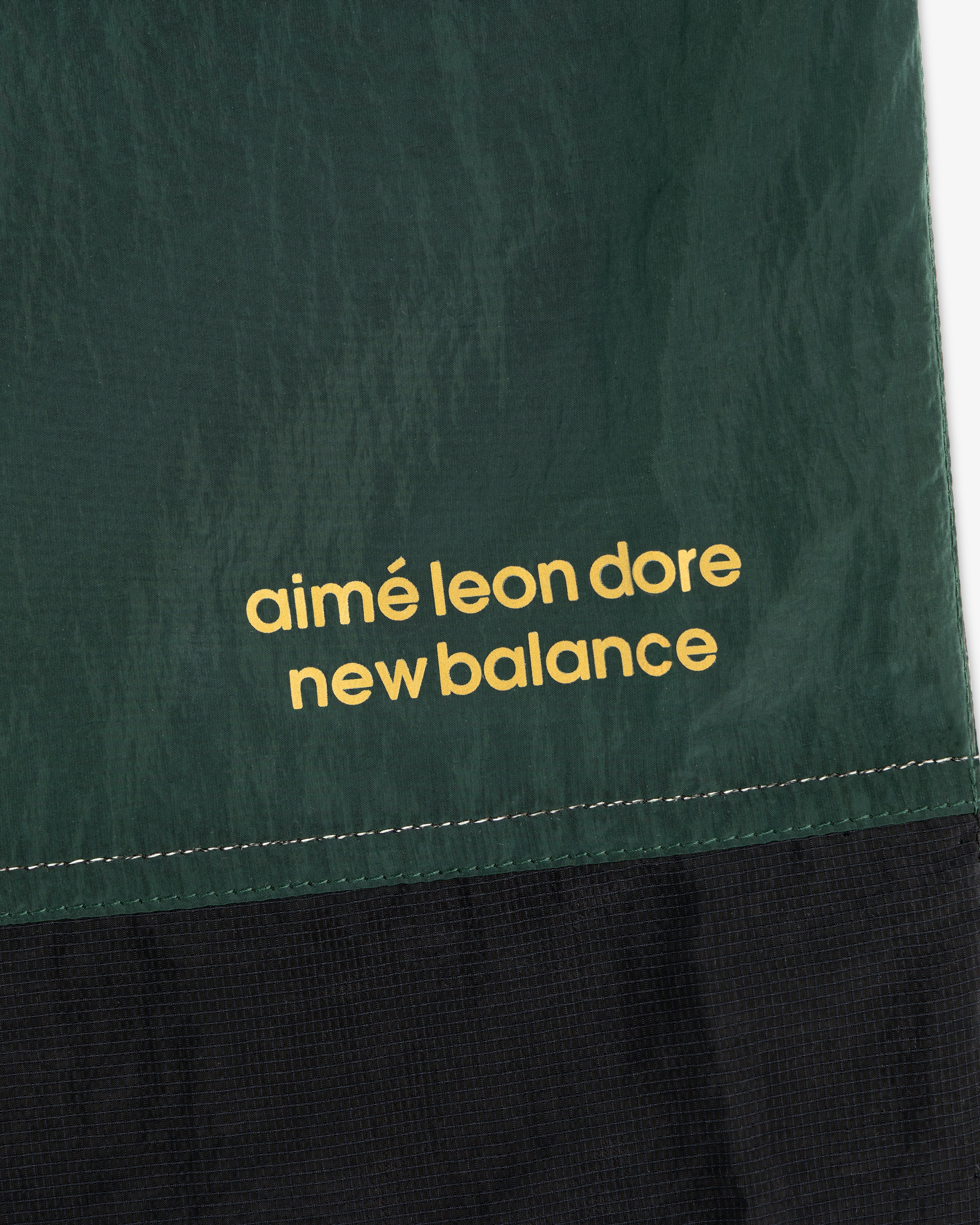 Green and black ALD / New Balance Lightweight Nylon Warmup Pant with yellow branding printed on fabric.