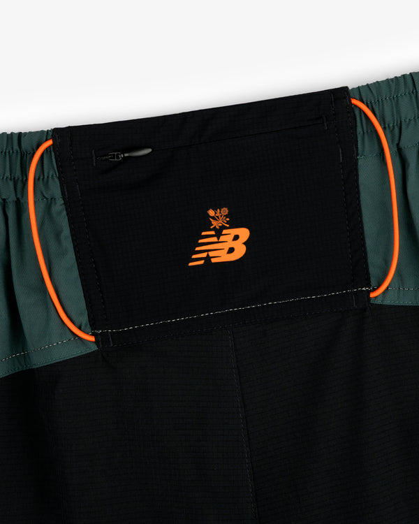 Close-up of ALD / New Balance Performance Lightweight Running Short in black and green with orange logo and trim.