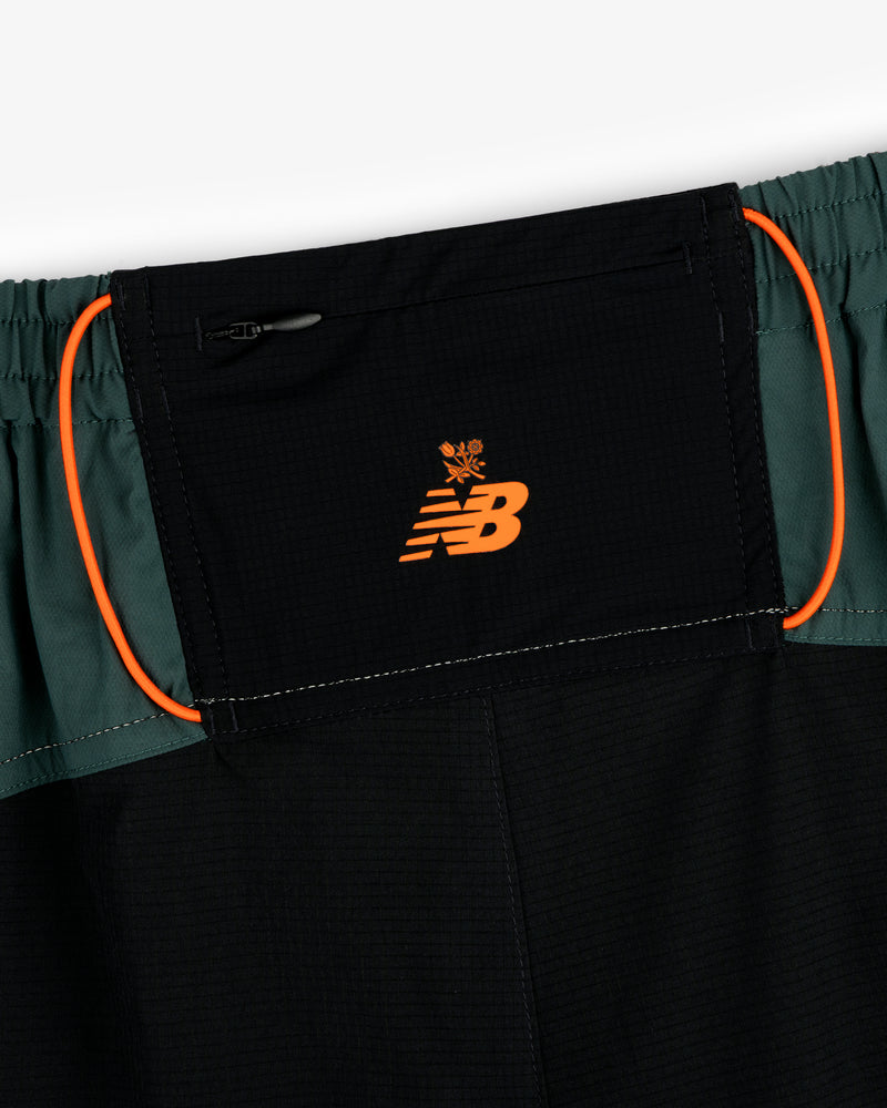 Close-up of ALD / New Balance Performance Lightweight Running Short in black and green with orange logo and trim.