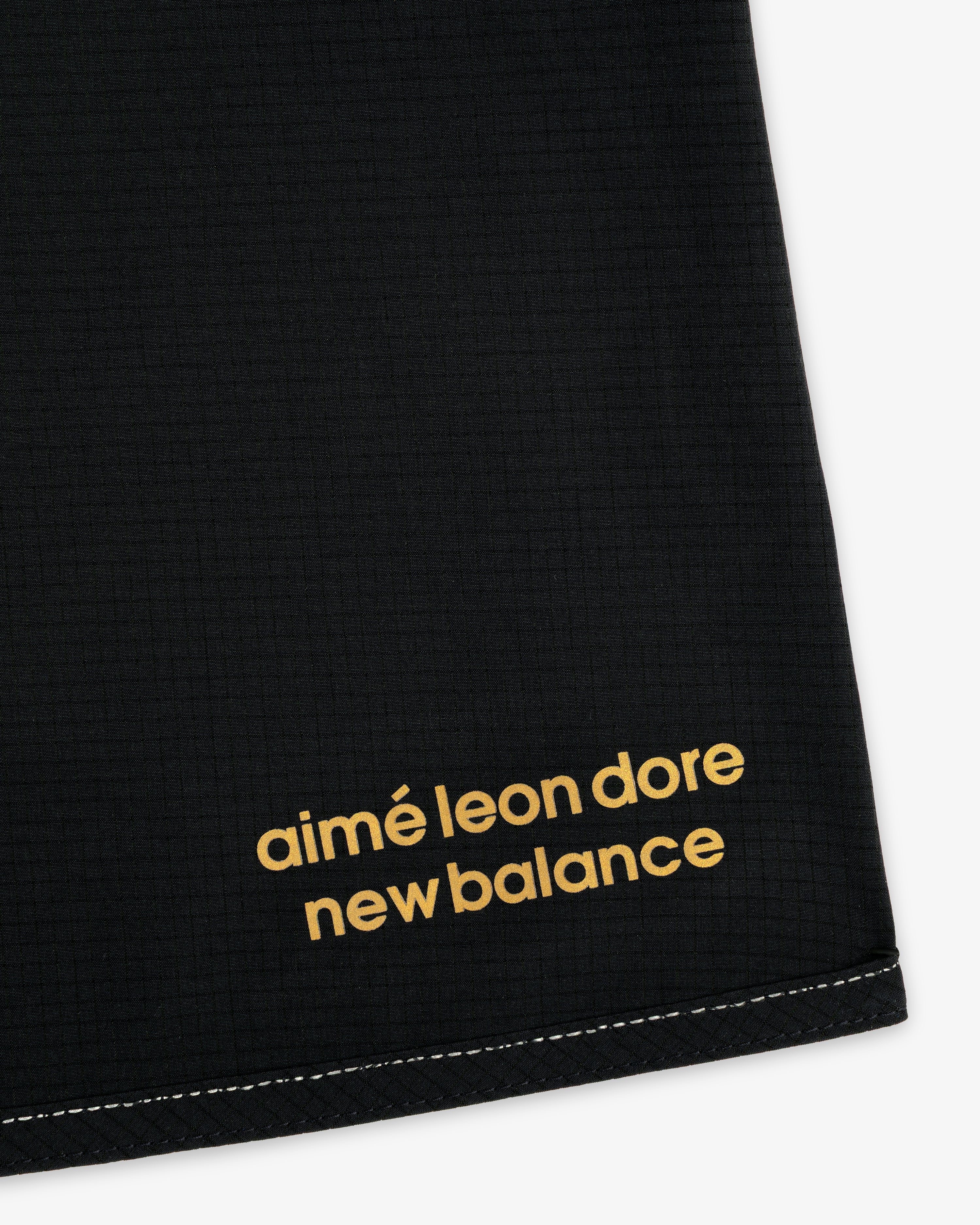 Close-up of black ALD / New Balance Performance Lightweight Running Short with yellow logo in the corner.