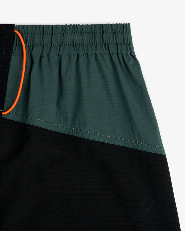 Close-up of ALD / New Balance Performance Lightweight Running Short in green and black with elastic waist and orange drawstring.