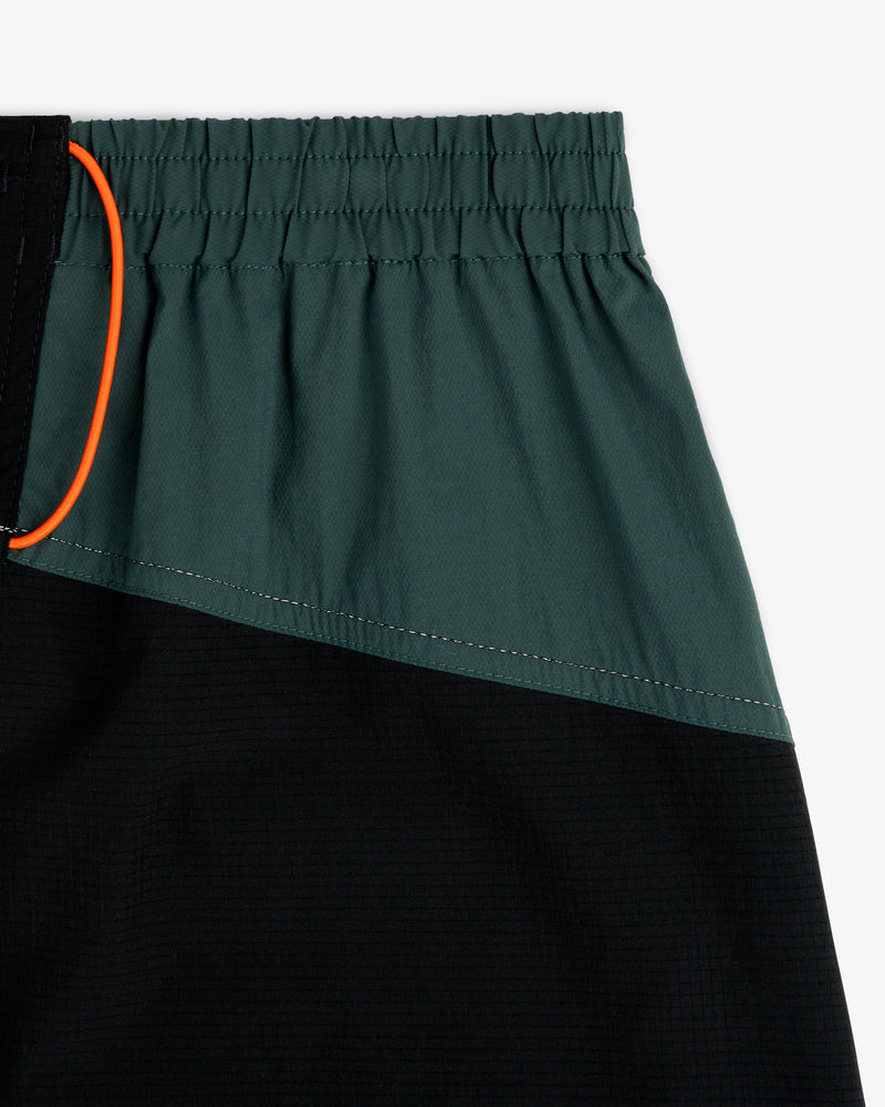 Close-up of ALD / New Balance Performance Lightweight Running Short in green and black with elastic waist and orange drawstring.