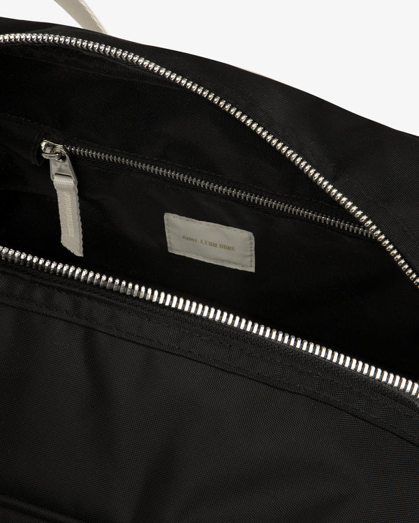 Close-up of an open Nylon Duffle Bag with a silver zipper and small inner pocket featuring a white label.