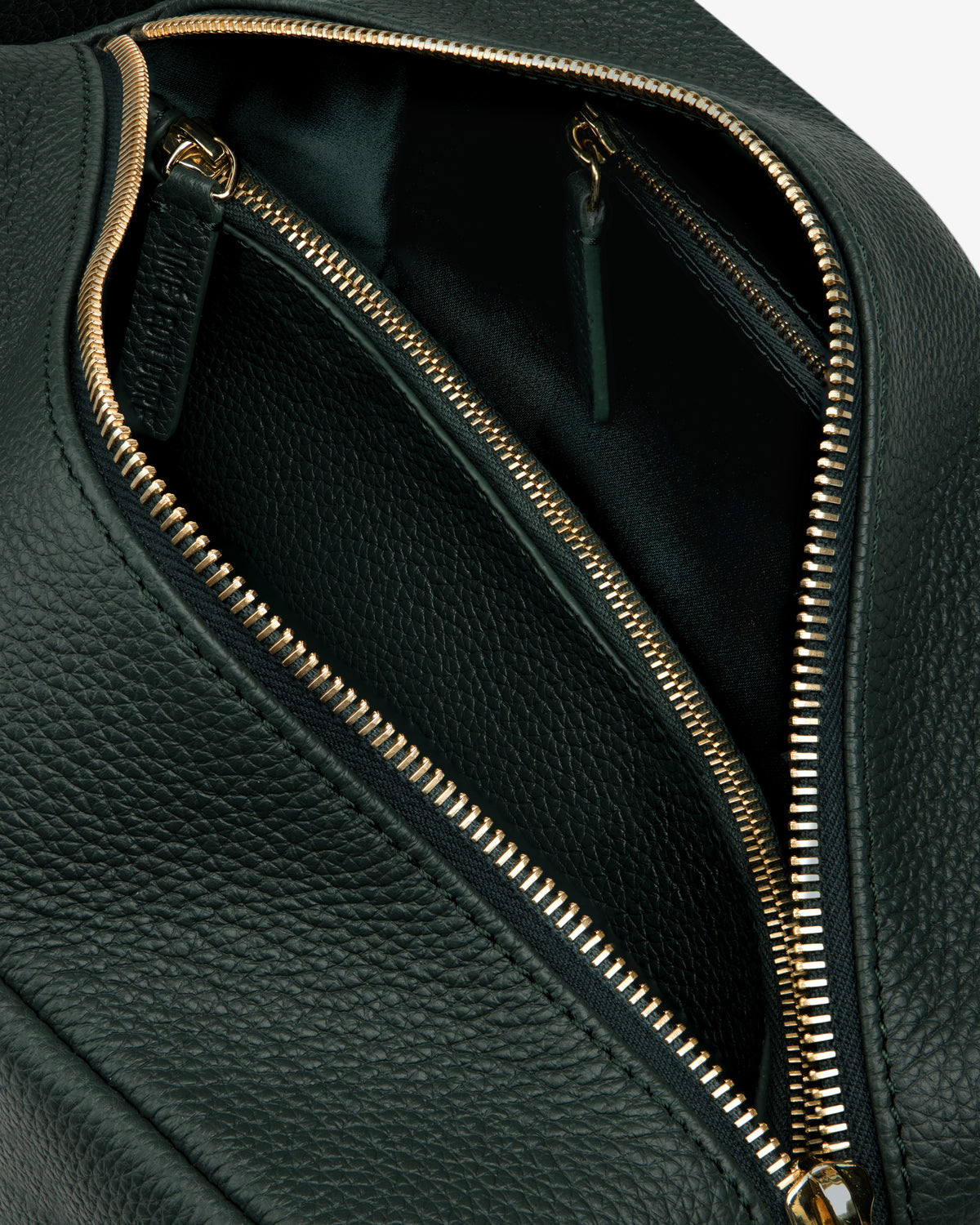 Close-up of the Leather Traveler Kit in black leather with gold zippers, highlighting its inner compartments.