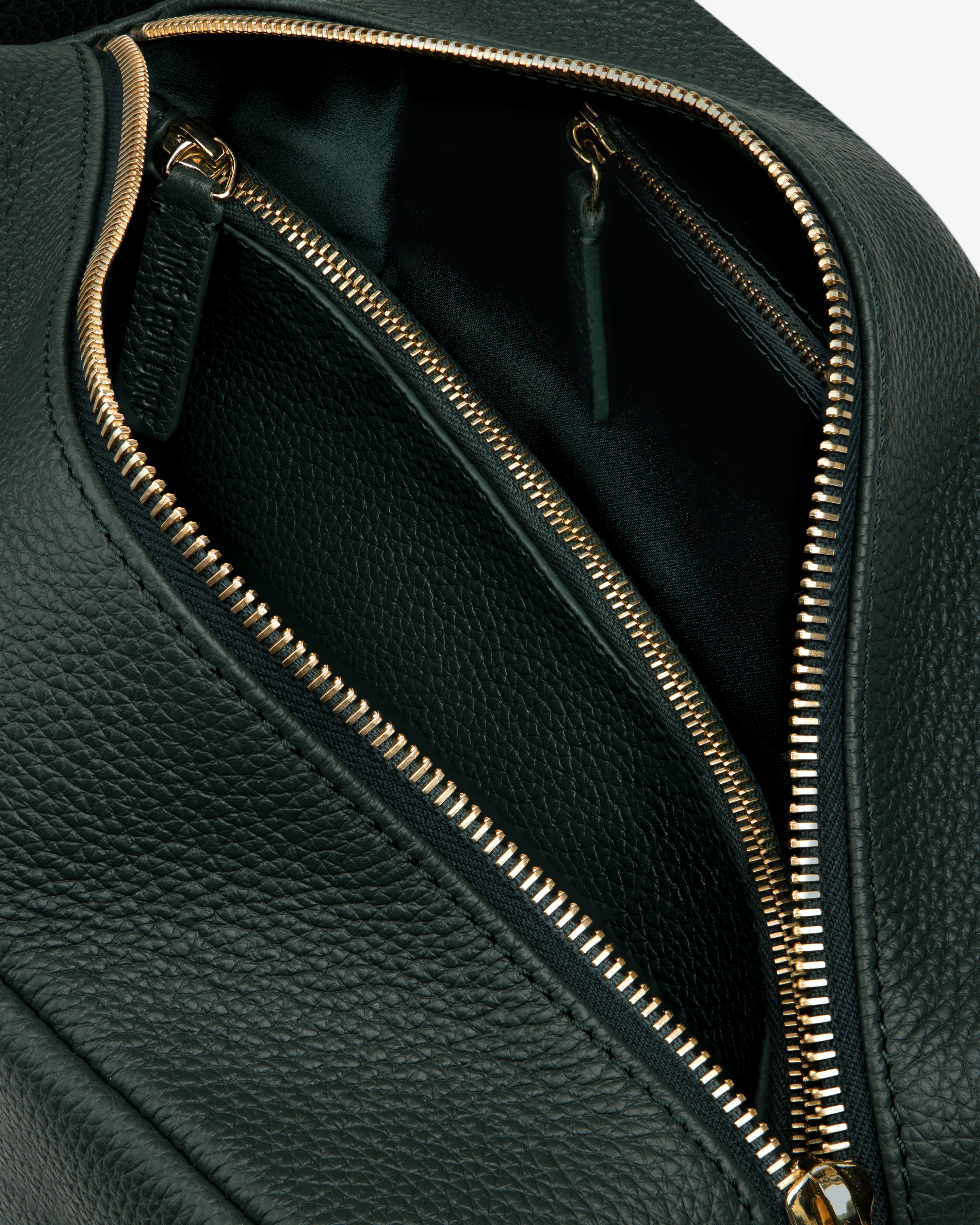 Close-up of the Leather Traveler Kit in black leather with gold zippers, highlighting its inner compartments.