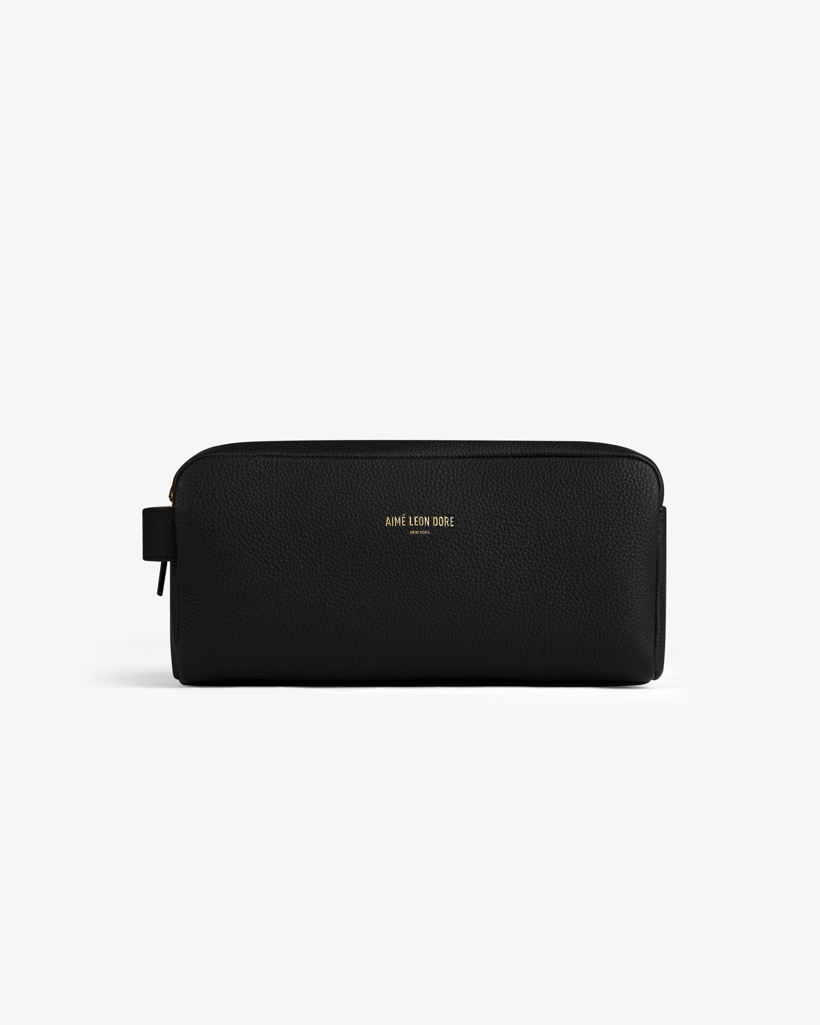 The Leather Traveler Kit is a black leather zippered toiletry bag with a side handle and gold AIMÉ LEON DORE branding.