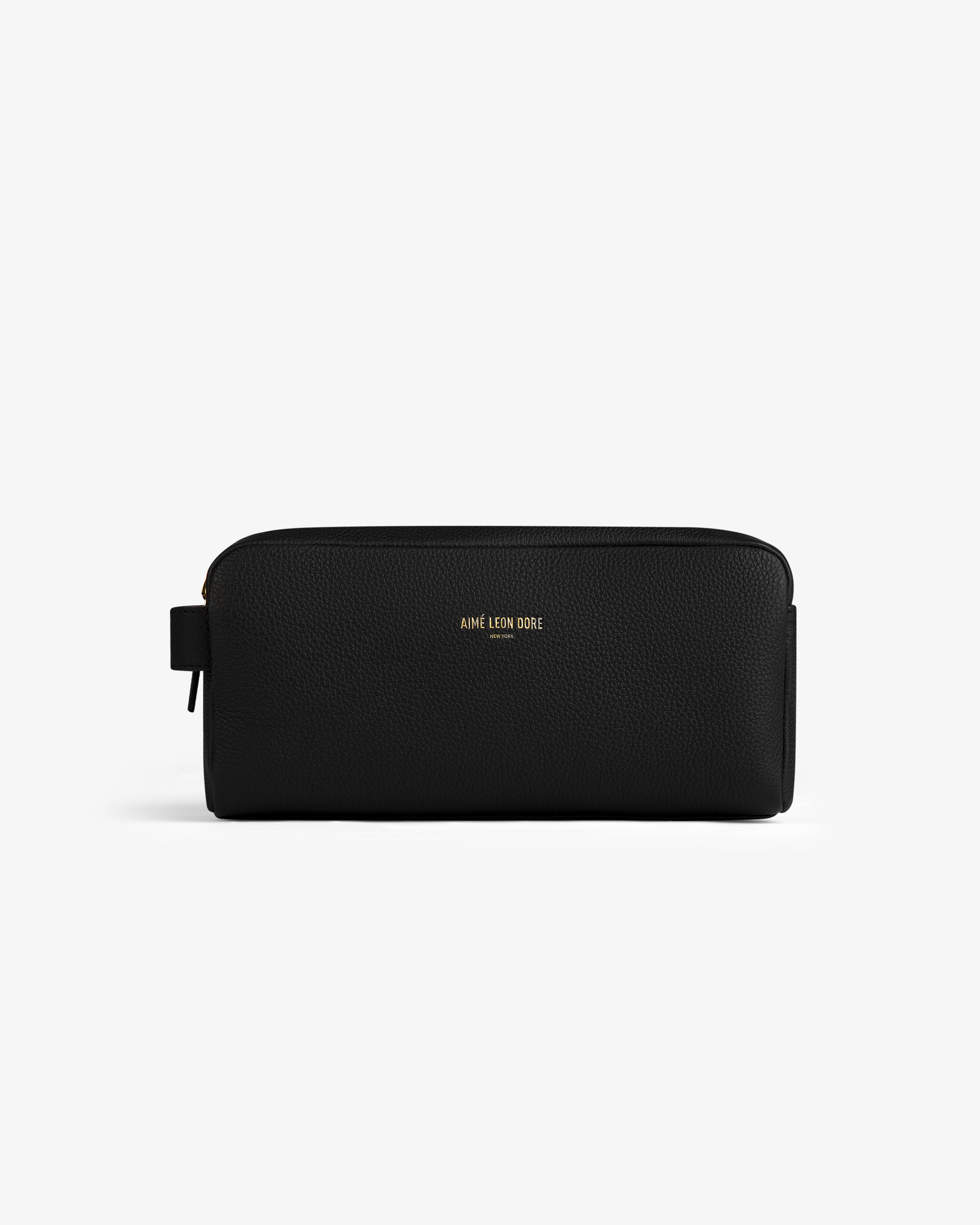 The Leather Traveler Kit is a black leather zippered toiletry bag with a side handle and gold AIMÉ LEON DORE branding.