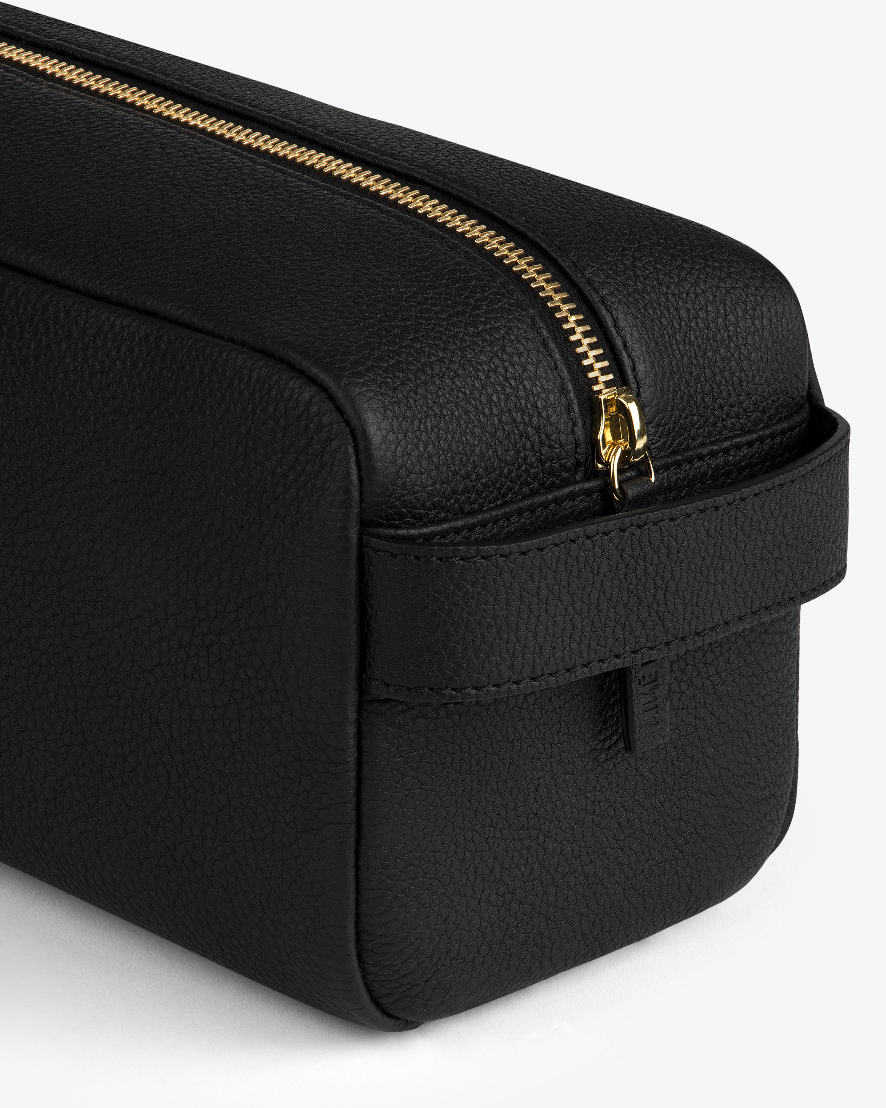 The Leather Traveler Kit—a black leather toiletry bag with a gold zipper and side handle—on a white background.
