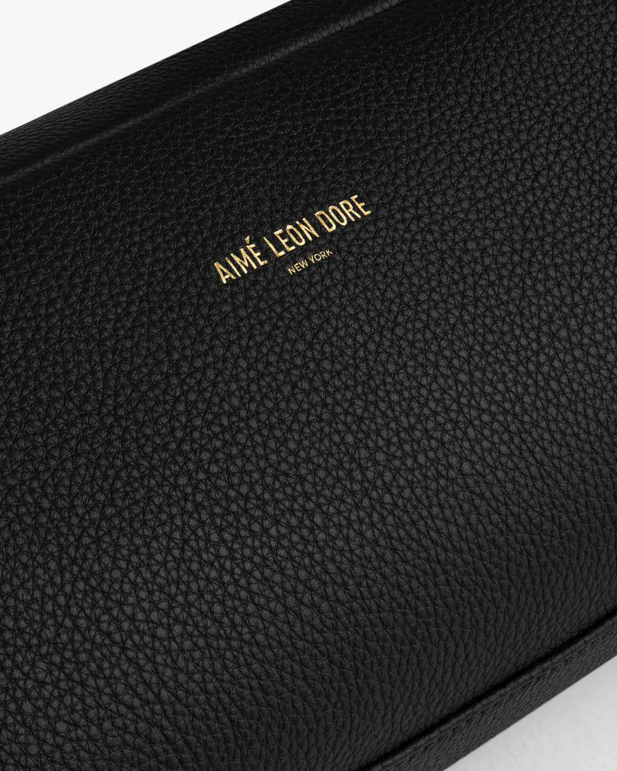 Close-up of the Leather Traveler Kit in black textured leather with AIMÉ LEON DORE NEW YORK embossed in gold.