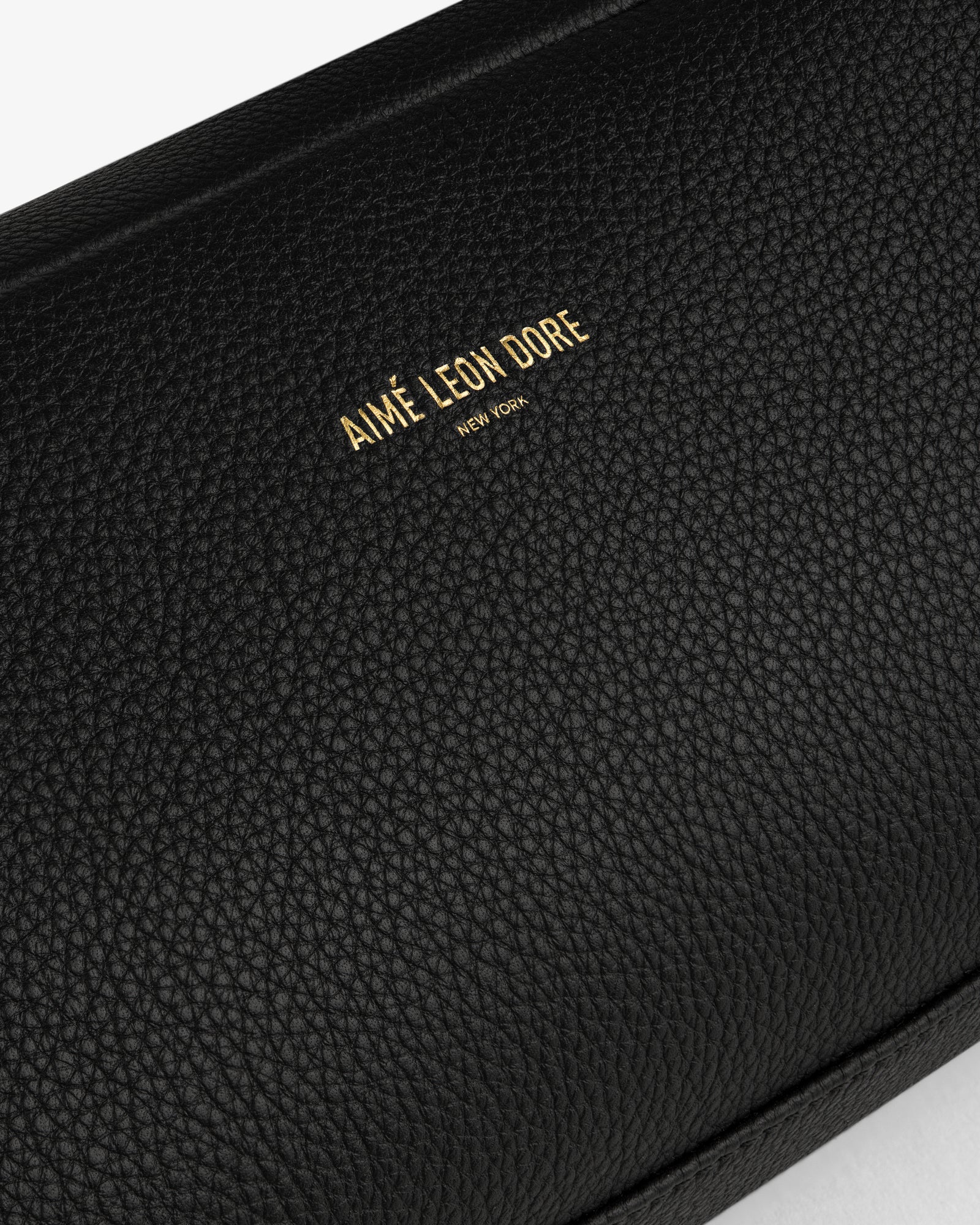 Close-up of the Leather Traveler Kit in black textured leather with AIMÉ LEON DORE NEW YORK embossed in gold.