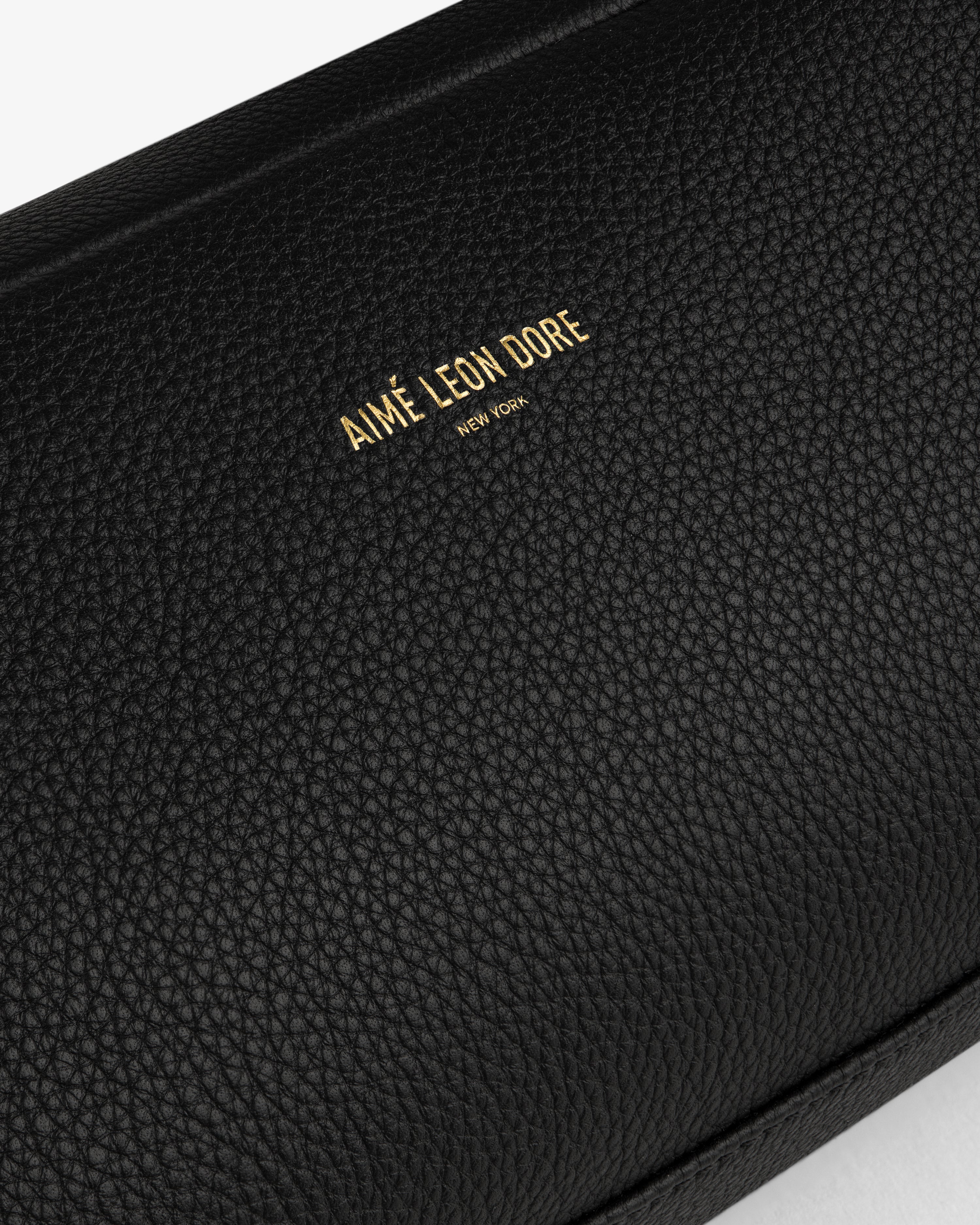 Close-up of the Leather Traveler Kit in black textured leather with AIMÉ LEON DORE NEW YORK embossed in gold.