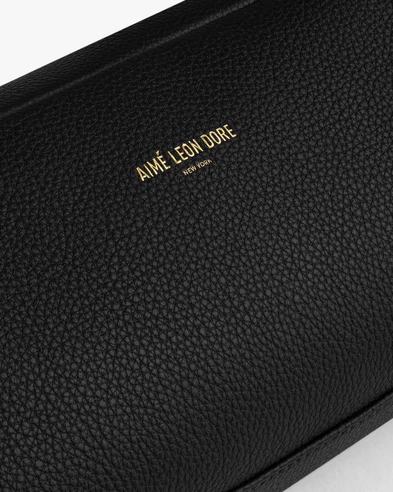 Close-up of the Leather Traveler Kit in black textured leather with AIMÉ LEON DORE NEW YORK embossed in gold.