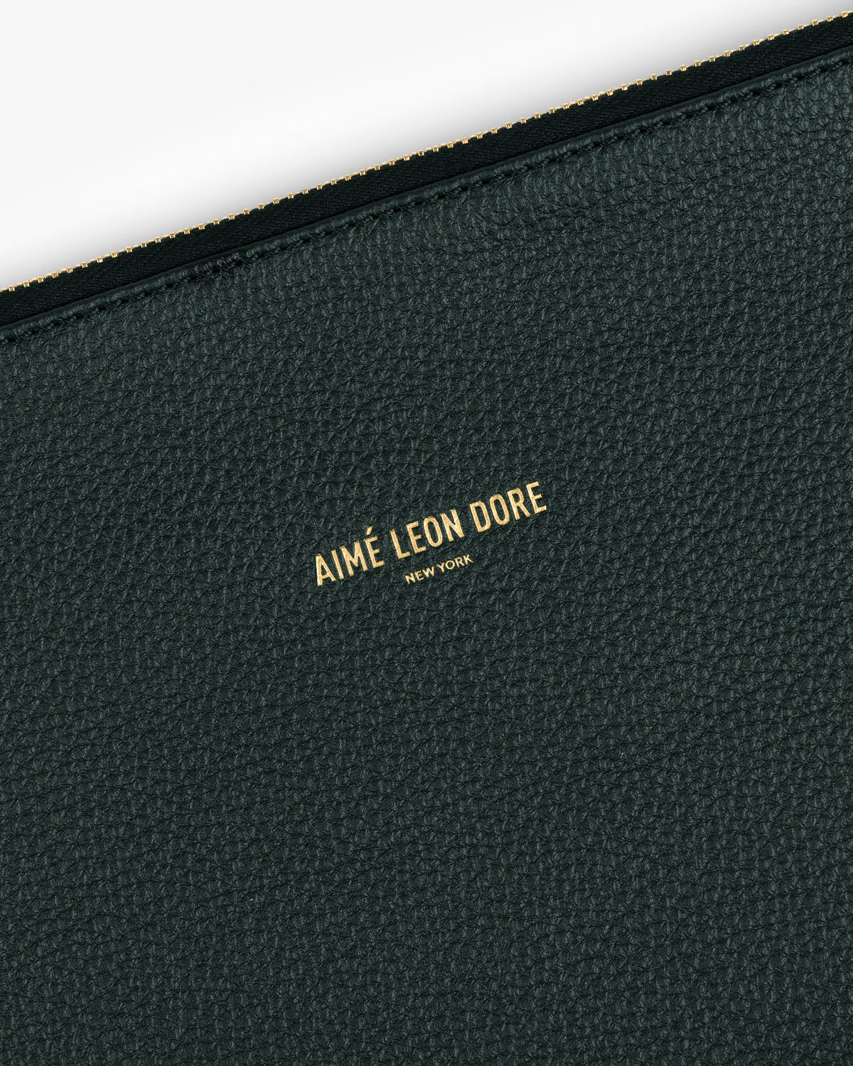 Close-up of a dark green Small Leather Pouch with AIMÉ LEON DORE NEW YORK embossed in gold.