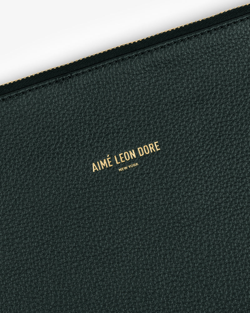 Close-up of a dark green Small Leather Pouch with AIMÉ LEON DORE NEW YORK embossed in gold.