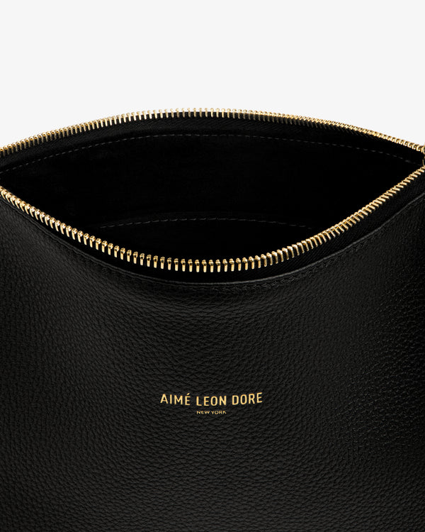 Close-up of an open Small Leather Pouch in black with a gold zipper and “AIMÉ LEON DORE NEW YORK” in gold lettering.