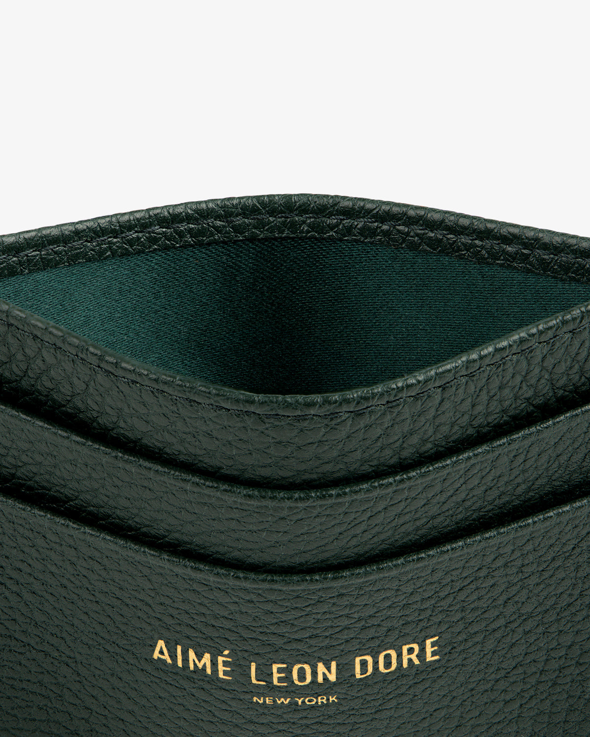 Close-up of a textured black Leather Card Holder with AIMÉ LEON DORE NEW YORK embossed in gold.
