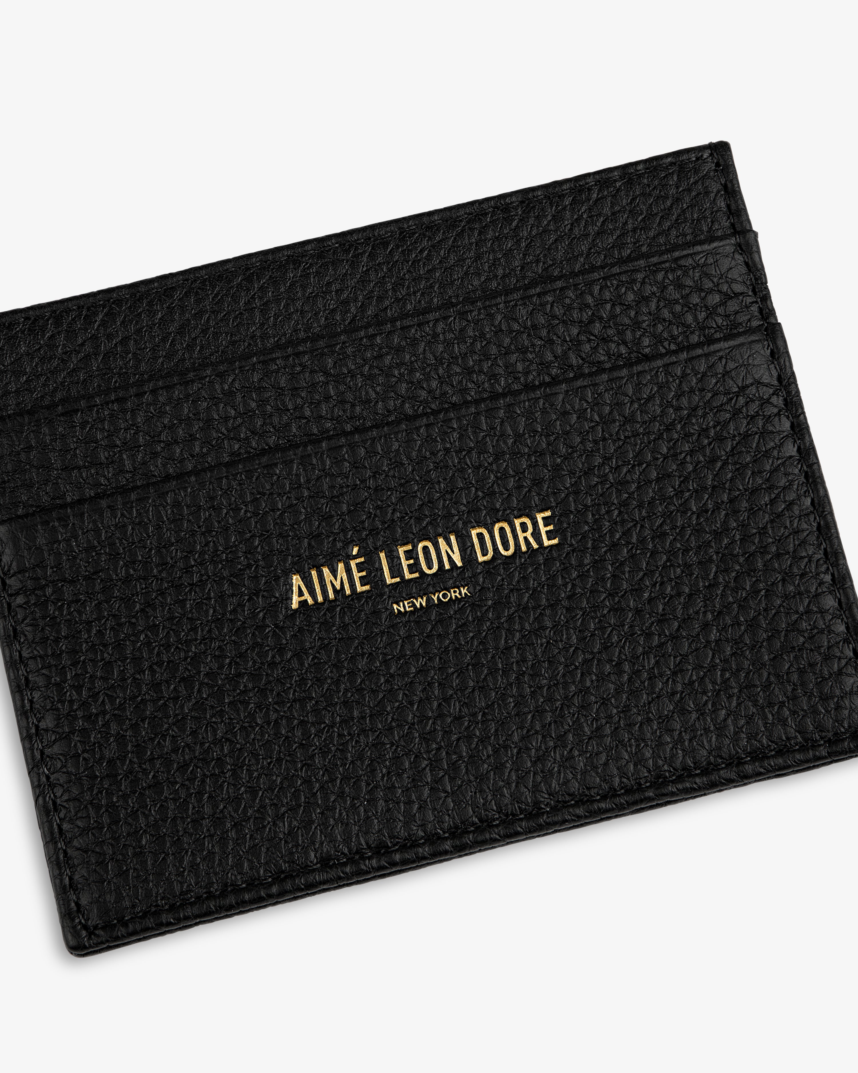 Black textured Leather Card Holder with AIMÉ LEON DORE NEW YORK embossed in gold on the front.