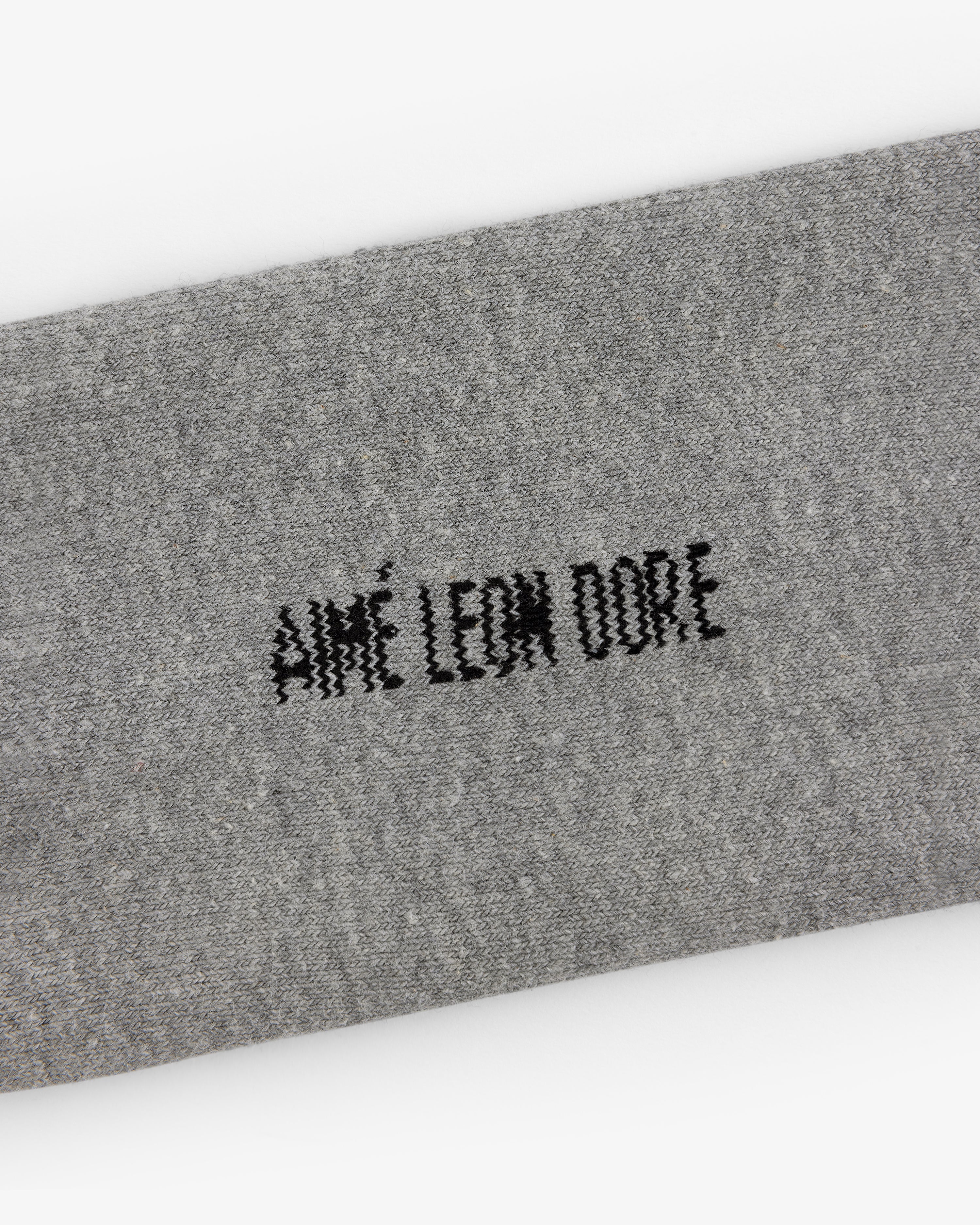 Gray fabric strip on Crew Sock 3-Pack with AIMÉ LEON DORE in black, stylized, pixelated text at the center.