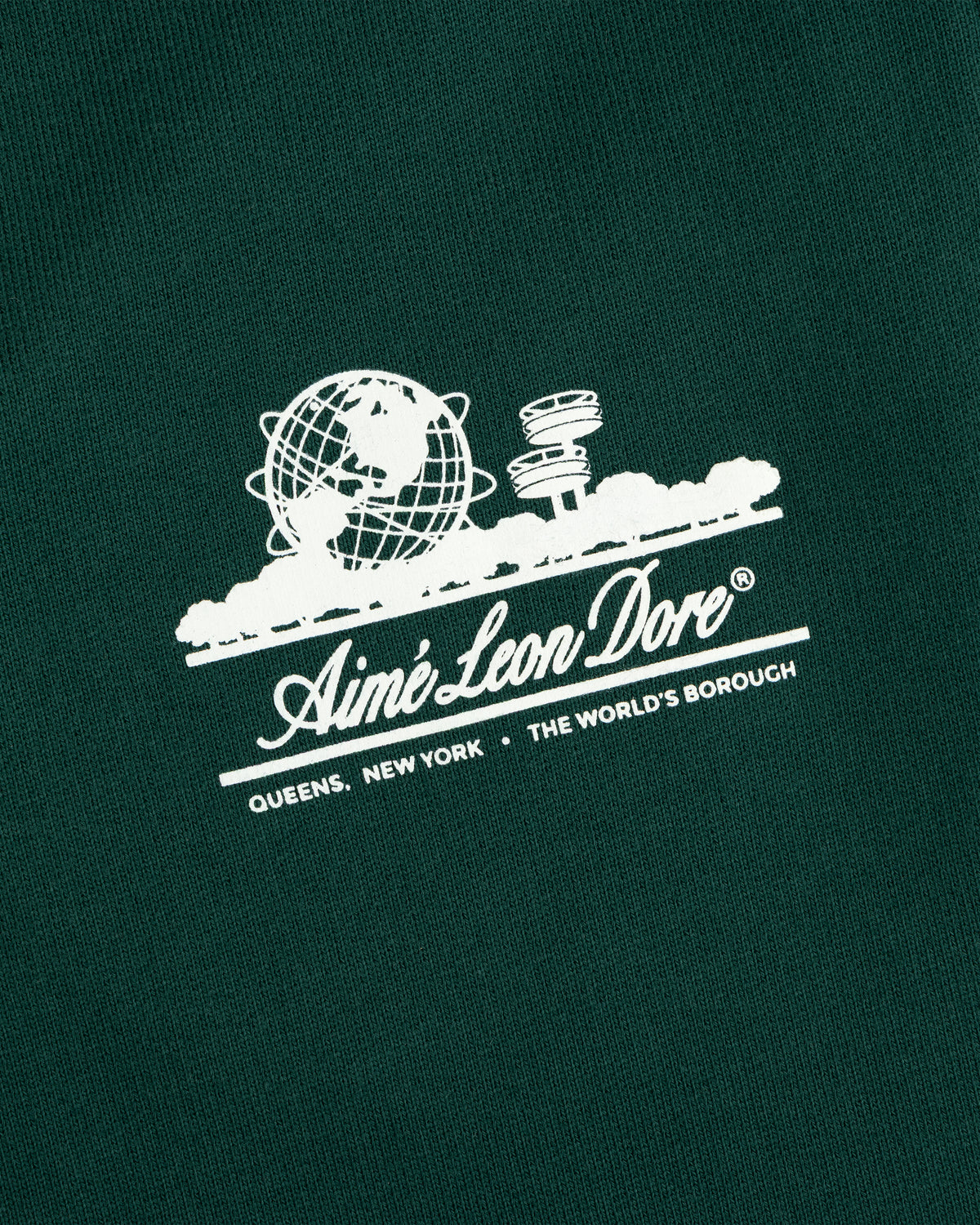 White Aimé Leon Dore Unisphere logo with globe, UFO, and text on dark green Unisphere Sweatpants.