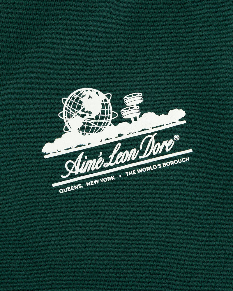 White Aimé Leon Dore Unisphere logo with globe, UFO, and text on dark green Unisphere Sweatpants.