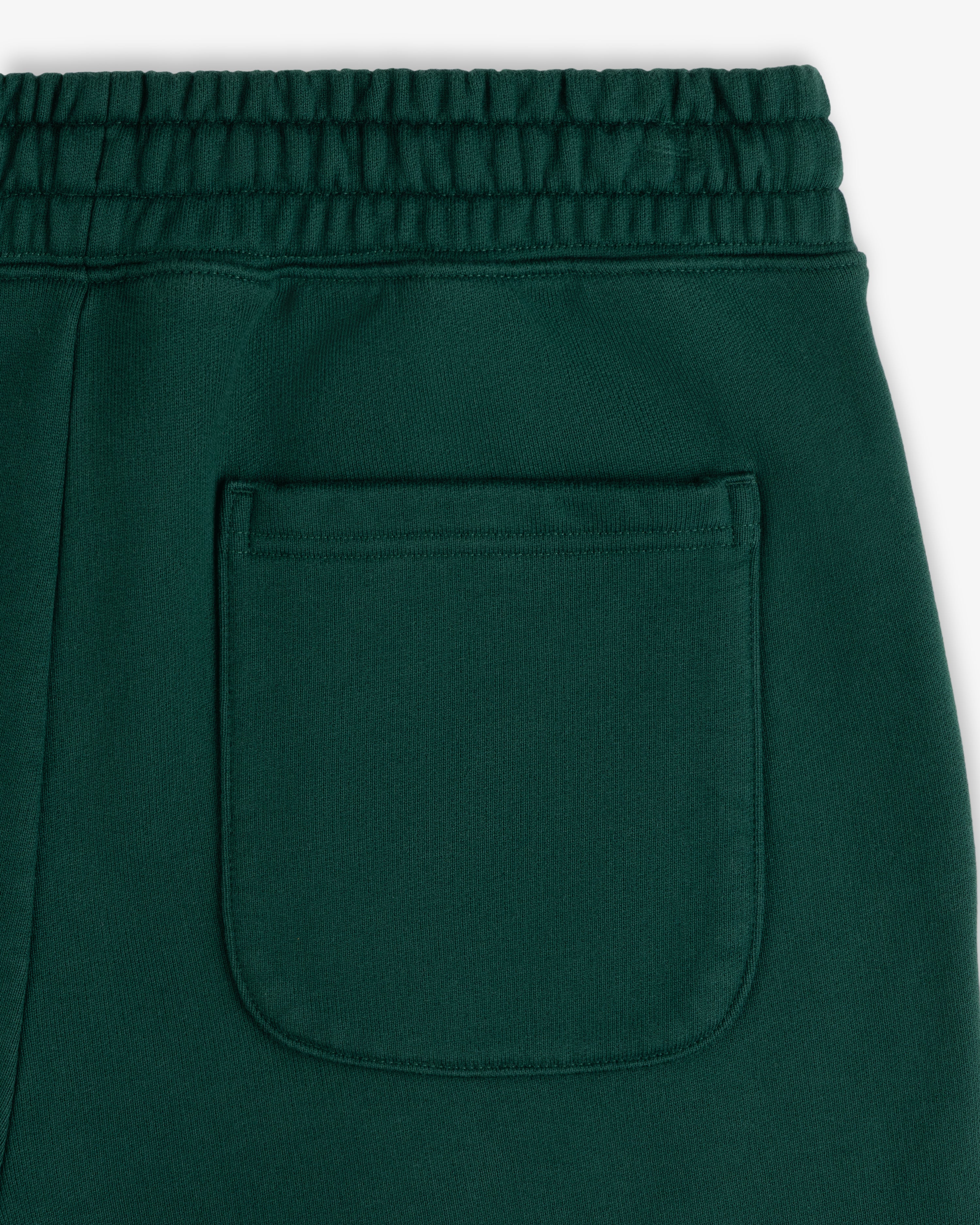 Close-up of Unisphere Sweatpants in green, featuring an elastic waistband and a single back pocket.