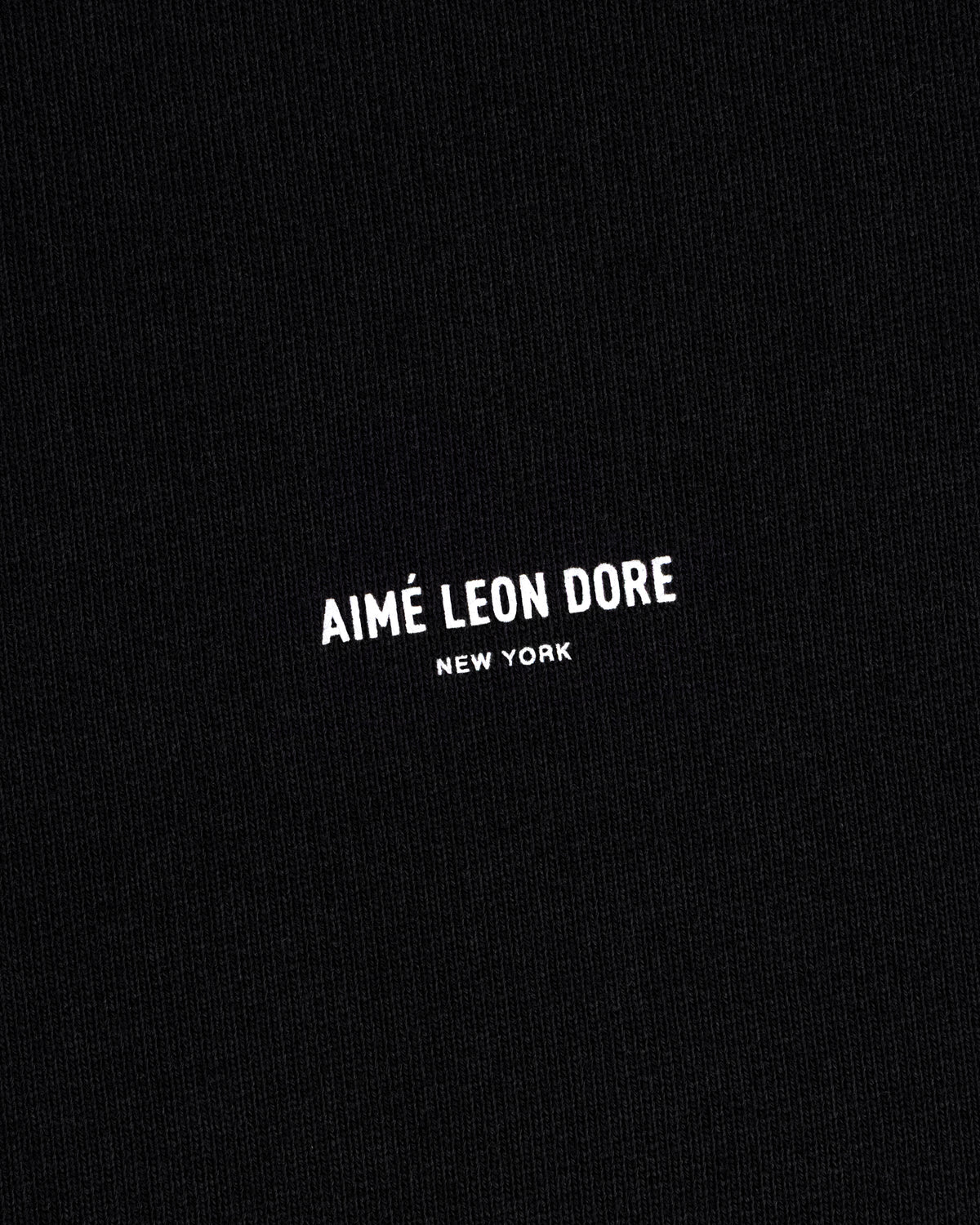 Black Micro Logo Crewneck Sweatshirt with small white "AIMÉ LEON DORE NEW YORK" text centered on fabric.
