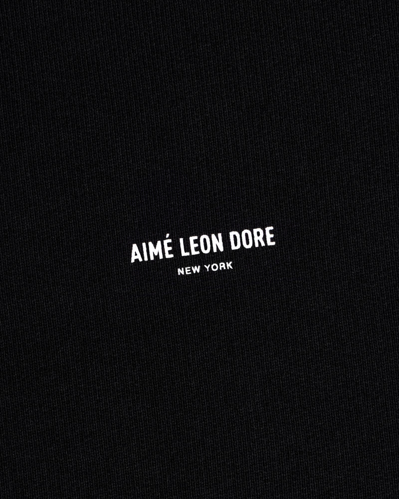 Black Micro Logo Crewneck Sweatshirt with small white "AIMÉ LEON DORE NEW YORK" text centered on fabric.