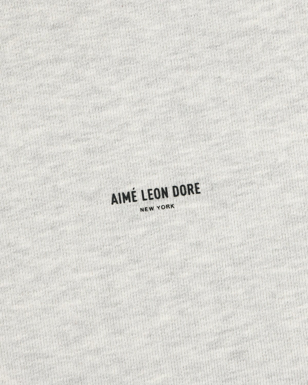 Close-up of a heather gray Micro Logo Crewneck Sweatshirt with small black AIMÉ LEON DORE NEW YORK at the center.