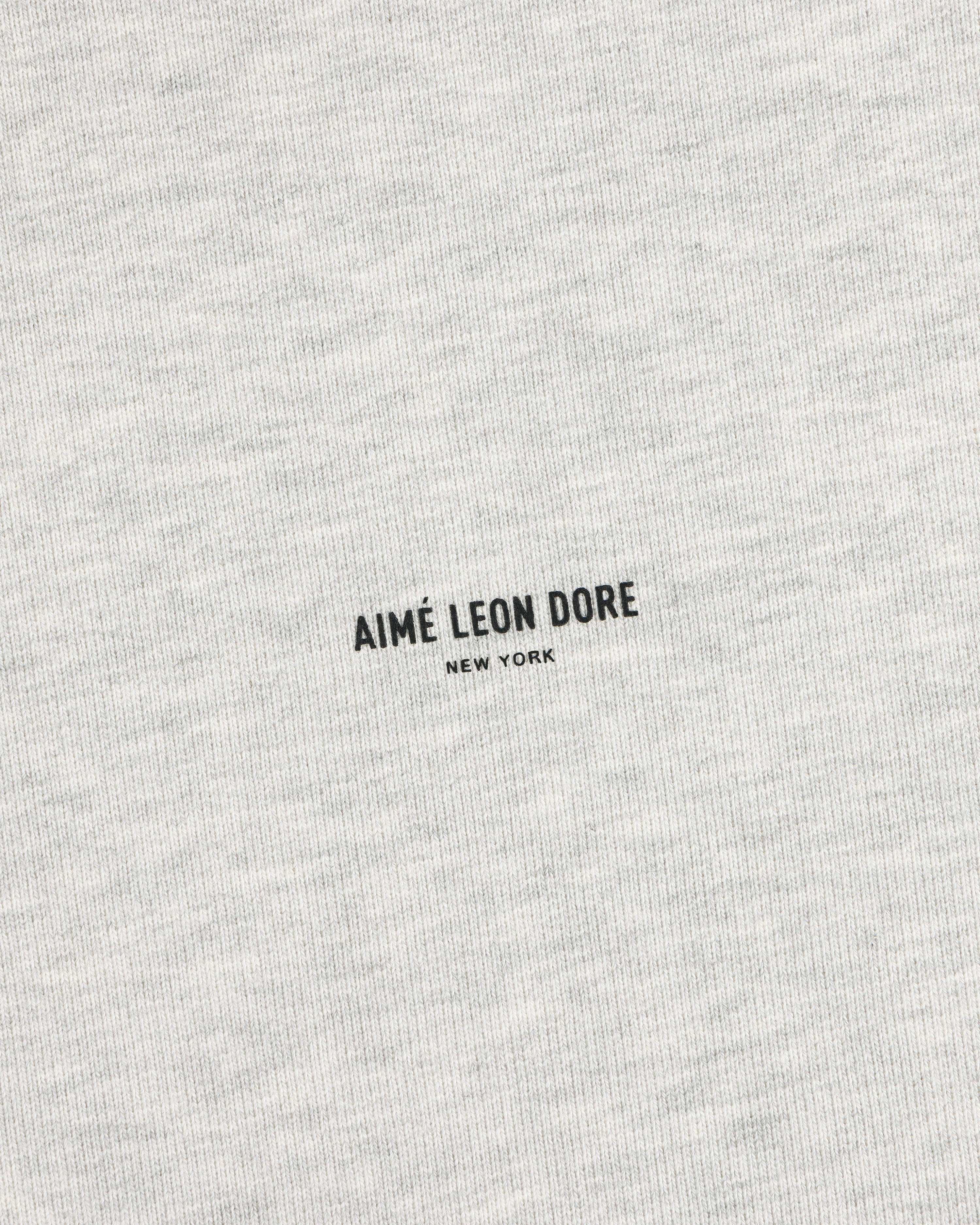 Close-up of a heather gray Micro Logo Crewneck Sweatshirt with small black AIMÉ LEON DORE NEW YORK at the center.