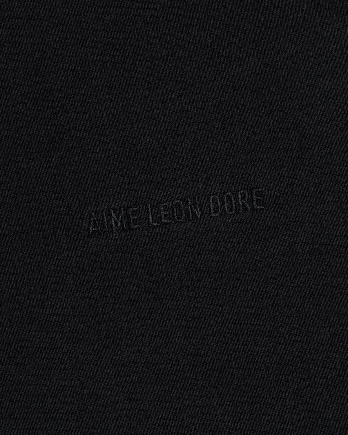 Close-up of black Tonal Logo Crewneck Sweatshirt with "AIME LEON DORE" embroidered in matching black thread.