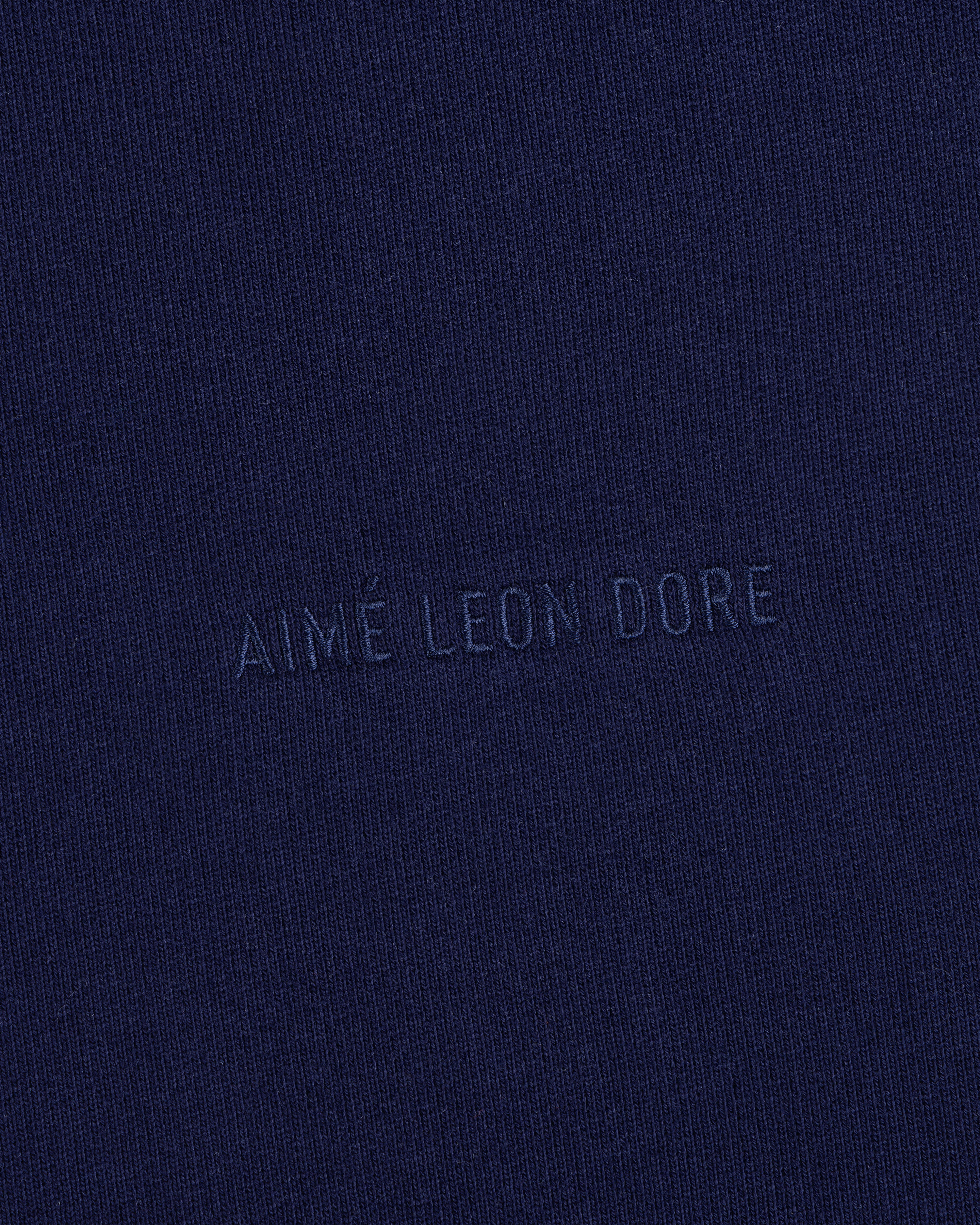 Close-up of navy blue Tonal Logo Crewneck Sweatshirt with AIMÉ LEON DORE subtly embossed in the center.