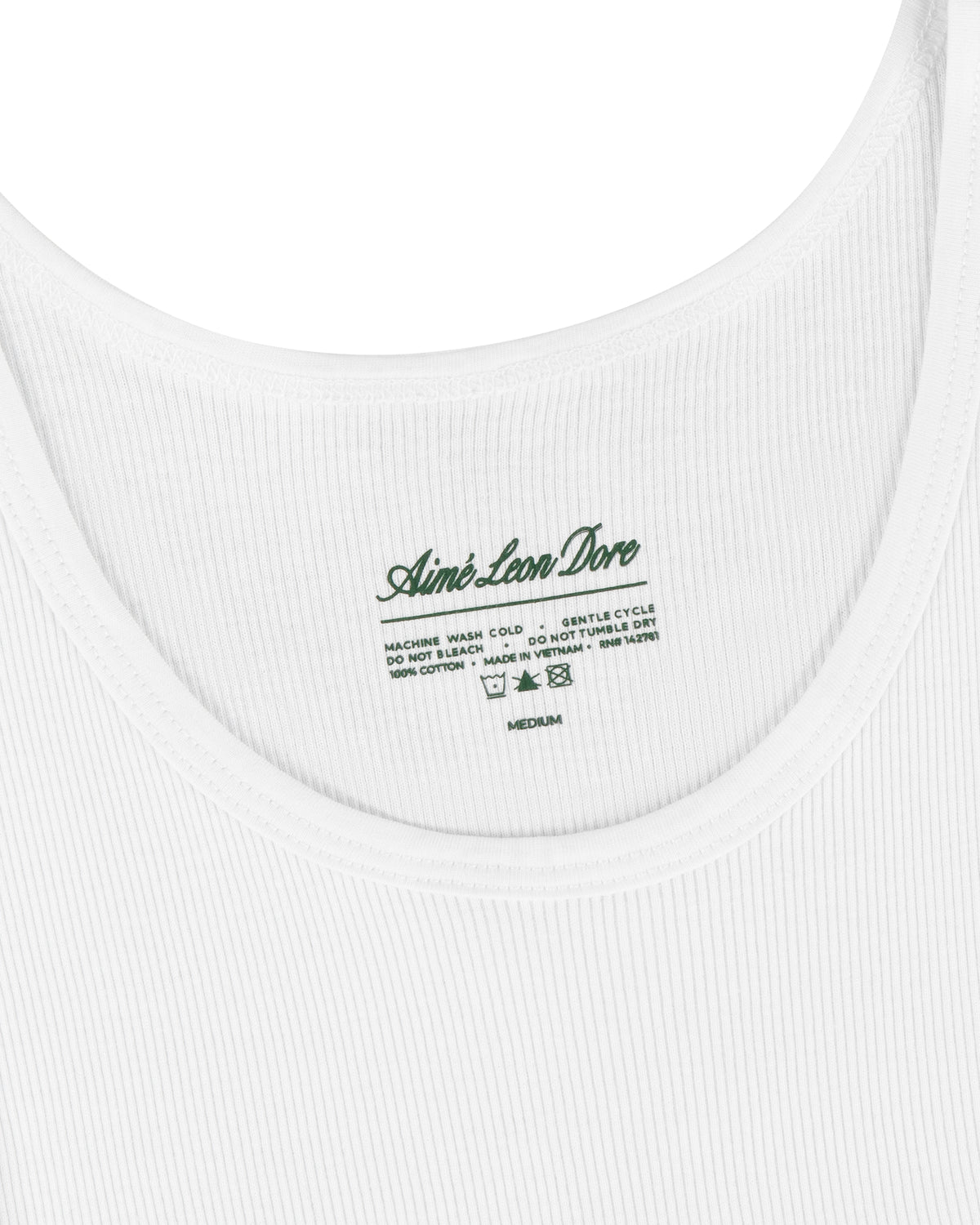 Close-up of a white Tank Top 3-Pack with a green Aimé Leon Dore label and care instructions inside the neckline.